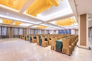 A large conference room with rows of chairs and tables, high ceilings, and modern lighting fixtures. - Xiliang Hotel (Wuwei)