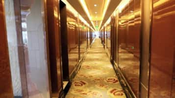 Un pasillo de hotel con paredes espejadas y una alfombra estampada.