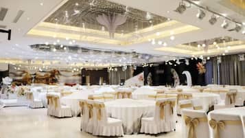 Une salle de banquet avec des tables rondes, des nappes blanches et des rubans dorés.