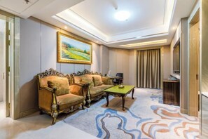 A room with a sofa set, a coffee table, a painting on the wall, and a patterned carpet. - Xiliang Hotel (Wuwei)