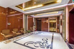 A hotel lobby with a reception desk, seating area, and a patterned floor. - Xiliang Hotel (Wuwei)