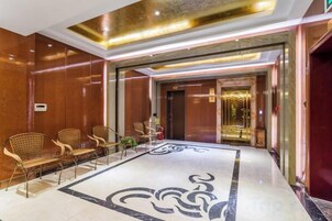 Un vestíbulo de hotel con mostrador de recepción, zona de estar y suelo estampado.