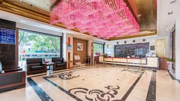 Un vestíbulo de hotel con mostrador de recepción, zona de estar y un llamativo elemento decorativo en el techo.