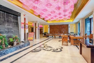 Vestíbulo de hotel con mostrador de recepción, zona de estar y techo decorativo.