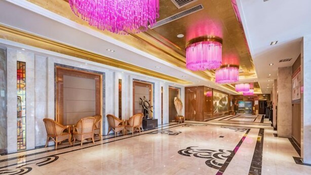 A hotel lobby with a marble floor, seating area, chandeliers, and a reception desk. - Xiliang Hotel (Wuwei)