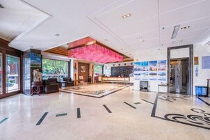 Un vestíbulo de hotel con mostrador de recepción, zona de estar y un amplio ventanal.