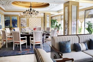 A dining area with a round table, chairs, and a chandelier.