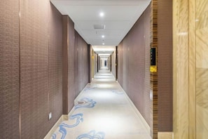 A long, narrow hotel corridor with a patterned carpet and a light-colored floor. - Xiliang Hotel (Wuwei)