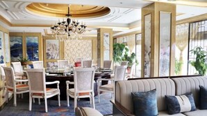 A spacious hotel lobby with a central dining area, a large sofa with cushions, and a chandelier. - Xiliang Hotel (Wuwei)