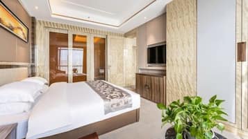 Una habitación de hotel moderna con una cama grande, un televisor, una planta y un armario.