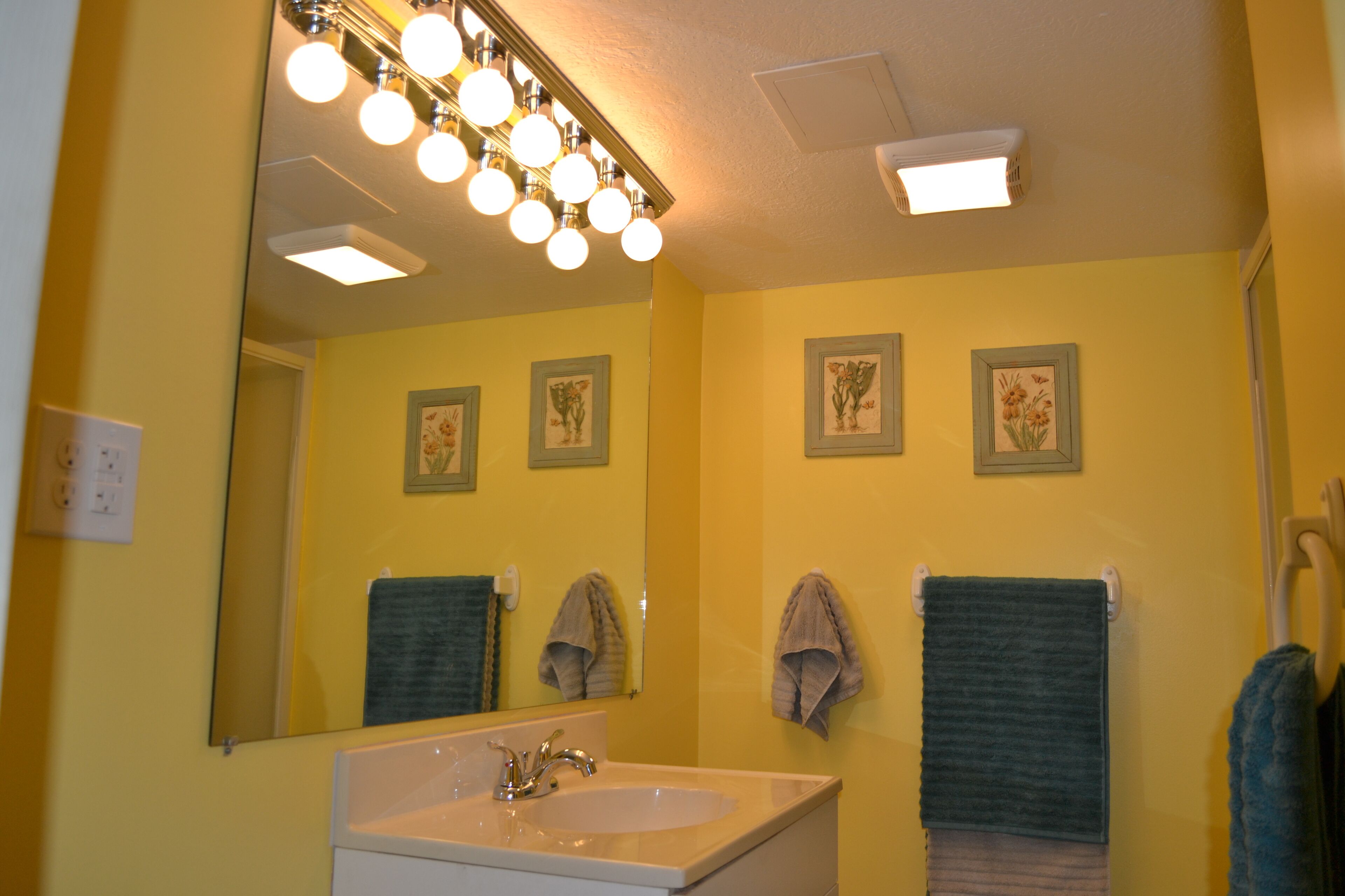 Une salle de bain équipée d’un lavabo, d’un miroir et de plusieurs serviettes.