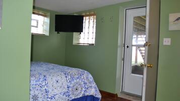 A room with a bed, a door, a window, and a wall-mounted television.