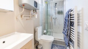 Un baño moderno con bañera, inodoro y ducha con mampara de vidrio.
