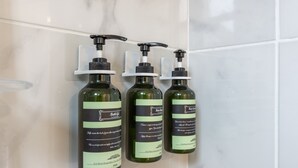 Tres botellas de gel de baño sobre una pared de azulejos blancos.
