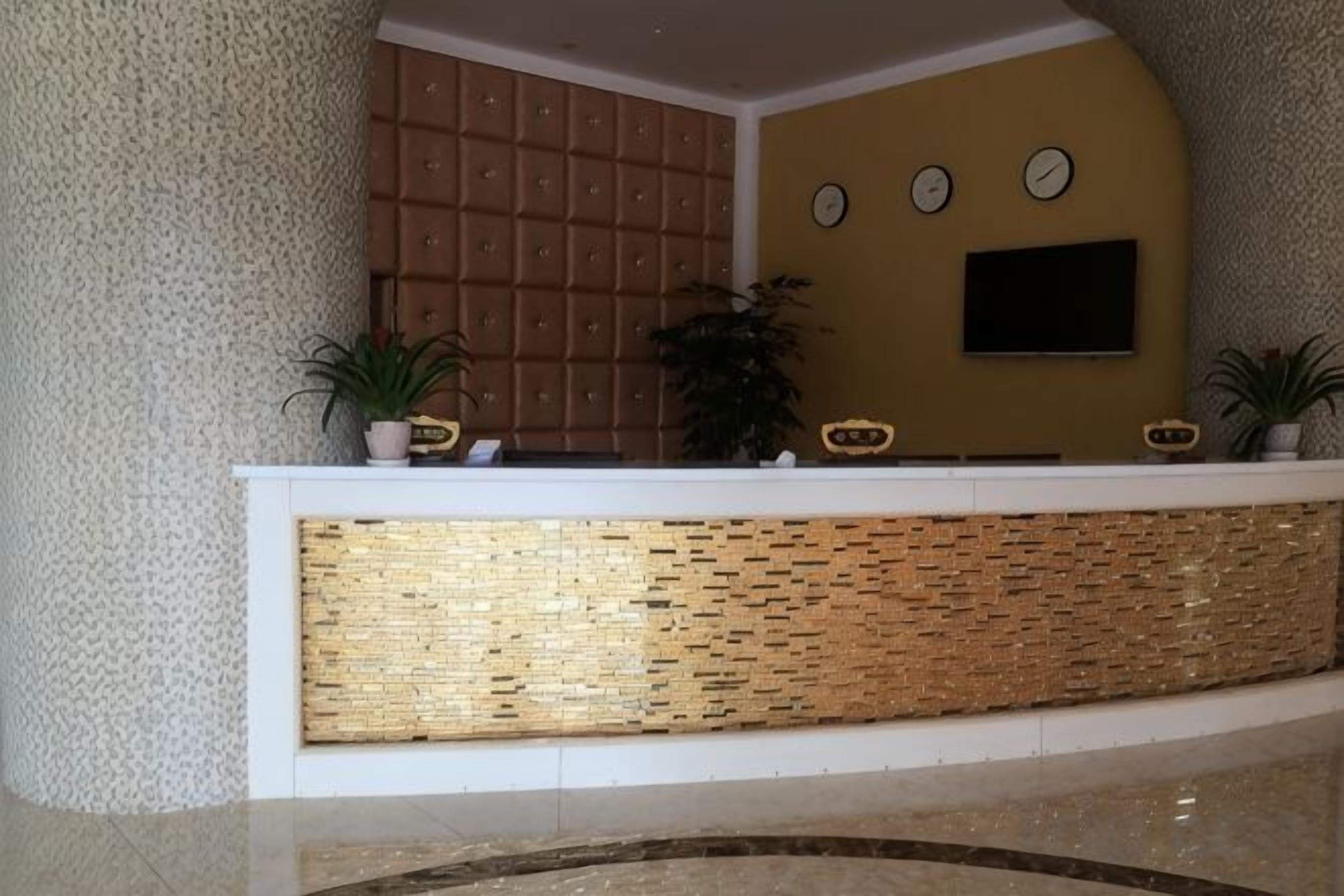 A reception desk with a patterned counter, a clock, and a television on the wall.