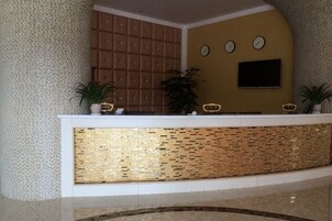 A reception area with a reception desk, a wall-mounted TV, and two clocks.