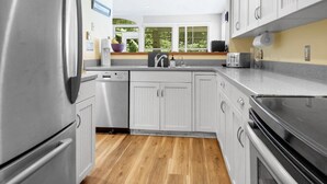 A modern kitchen with stainless steel appliances, white cabinetry, and a wooden floor. - Townhouse Cottage on Oceanfront Property Adj. Samoset Golf Resort+Lighthouse (Rockport)