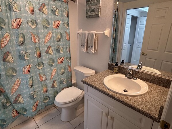 A bathroom with a toilet, sink, and mirror.