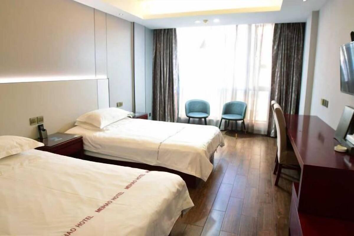 Ett hotellrum med två sängar, ett skrivbord, en stol och en TV.