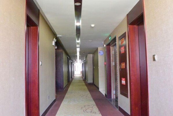 A hotel hallway with doors on both sides, a carpeted floor, and a light fixture on the ceiling. - Meihao Boutique Hotel (Pingyang)