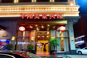 A hotel entrance with a sign, potted plants, and a car parked outside. - Meihao Boutique Hotel (Pingyang)