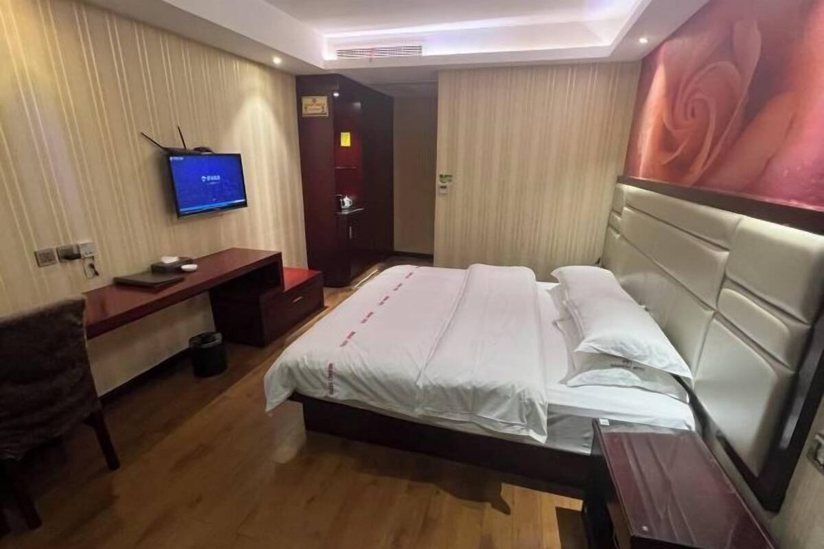 Ett hotellrum med en säng, ett skrivbord, en tv och en dörr.