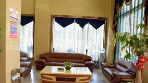 A living room with brown leather sofas, a central coffee table, and a potted plant. - Meihao Boutique Hotel (Pingyang)