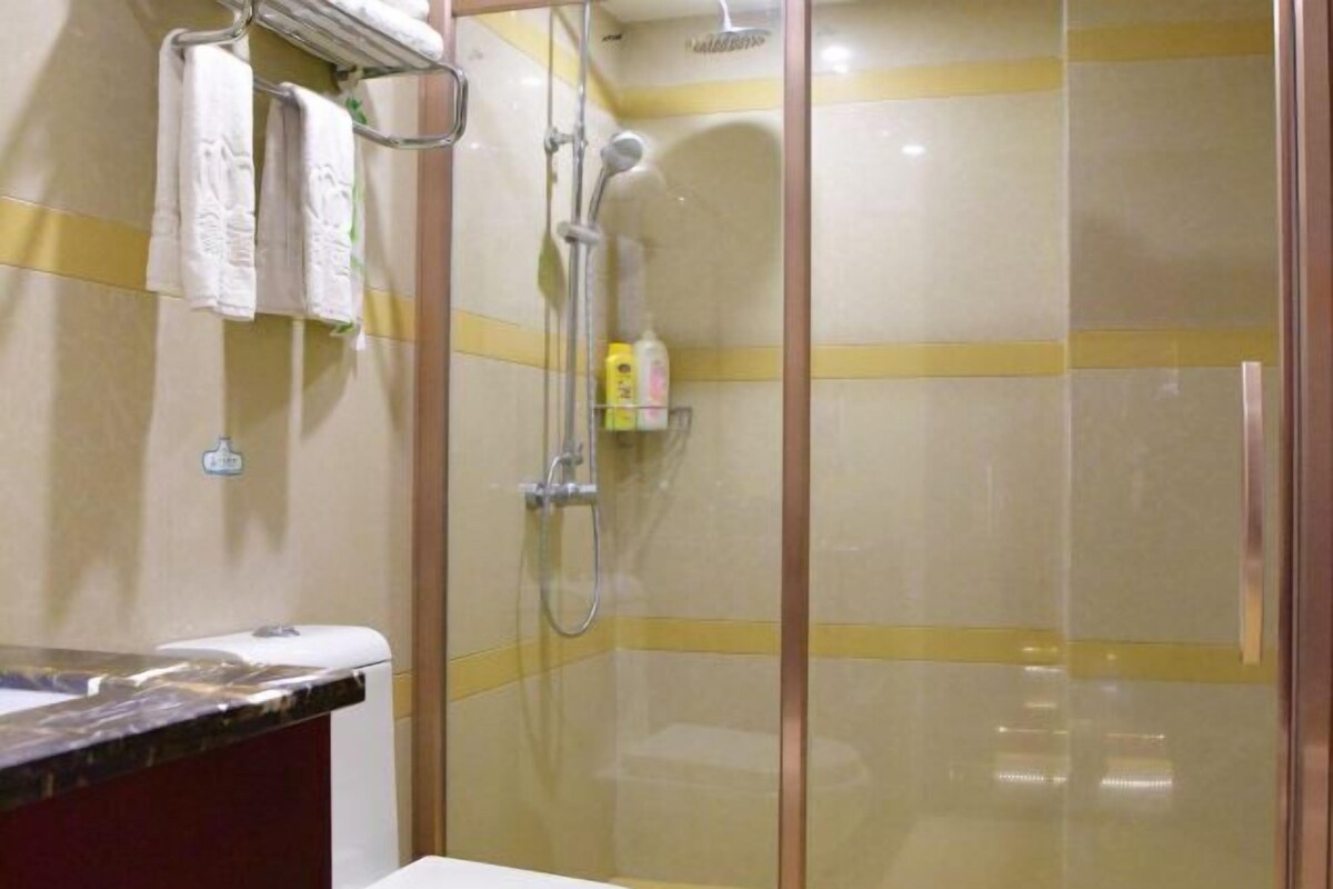 A shower area with a glass door, a towel rack with towels, and a small shelf with toiletries.