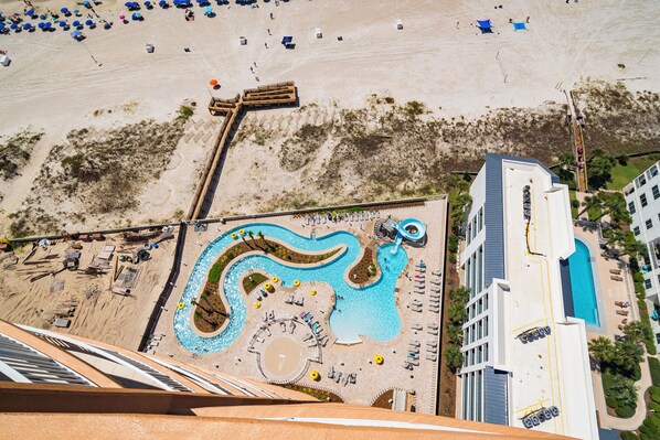 Vue aérienne d ’un complexe hôtelier doté d’une grande piscine, d’une plage de sable et d’un bâtiment à l’architecture moderne.