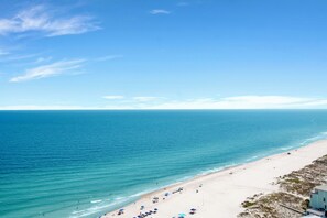 Une plage avec une eau d’un bleu limpide, un rivage sablonneux et quelques parasols.