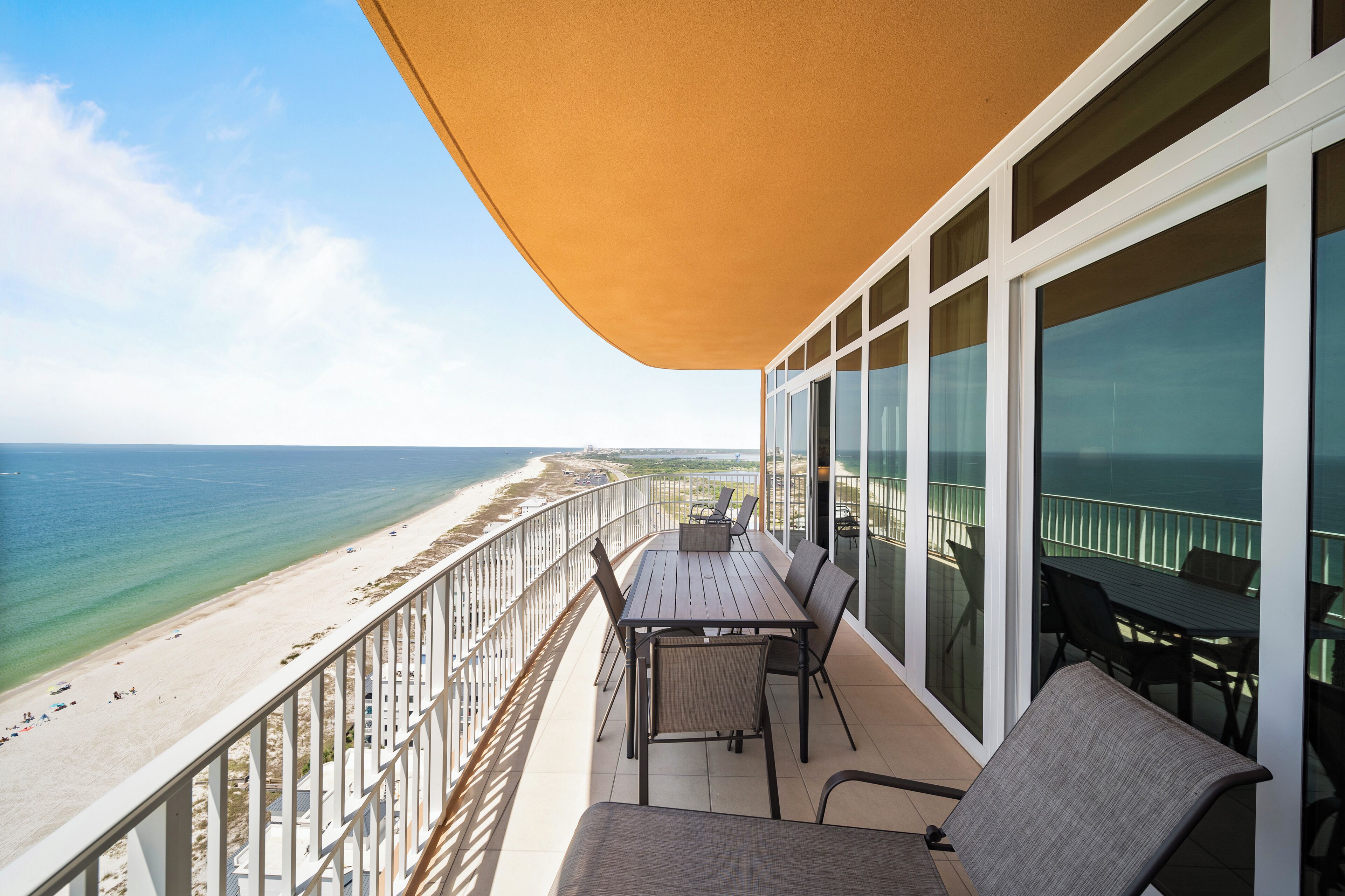 A balcony with a table and chairs overlooking a beach.