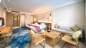 A hotel room with a bed, a sofa, a desk, and two chairs. - Hakkas Center Hotel (Meizhou)