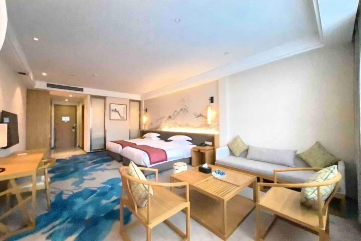A hotel room with a bed, a sofa, a desk, and two chairs.