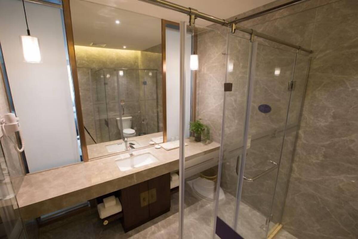 A modern bathroom with a glass-enclosed shower, a large mirror, and a vanity with a sink and countertop.