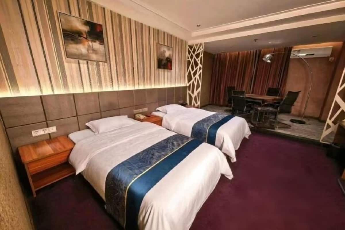 A hotel room with two beds, a desk, a chair, and a dining area.