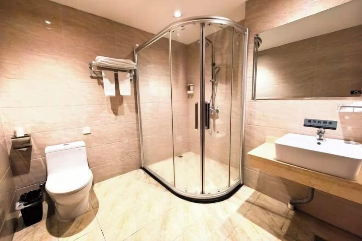 A modern bathroom with a glass-enclosed shower, a toilet, and a sink with a mirror above it.
