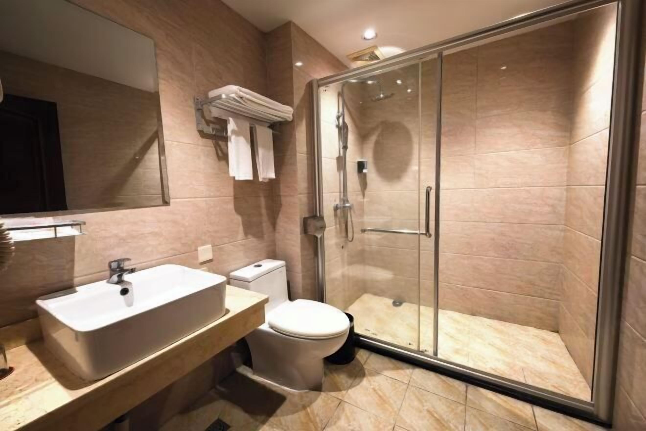 A modern bathroom with a glass-enclosed shower, a white sink, and a toilet.