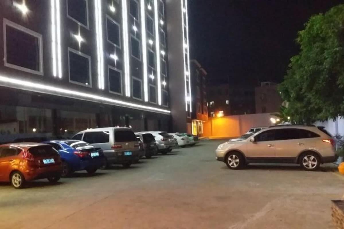A parking lot with several cars parked in front of a building with illuminated windows.