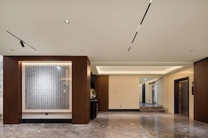 Un moderno vestíbulo de hotel con piso de mármol, una obra de arte enmarco y un mostrador de recepción.