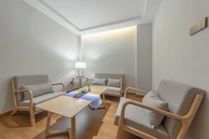 A modern, minimalist room with a wooden floor, two sofas, a small table, and a lamp. - Chuxiongzhou Hotel (Chuxiong City)