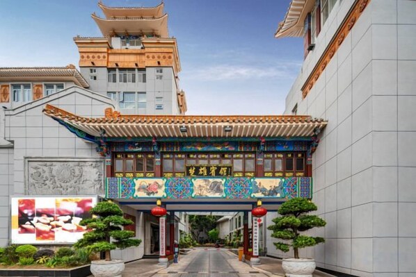 Una puerta tradicional china con diseños intrincados, que da acceso a un edificio de fachada moderna.