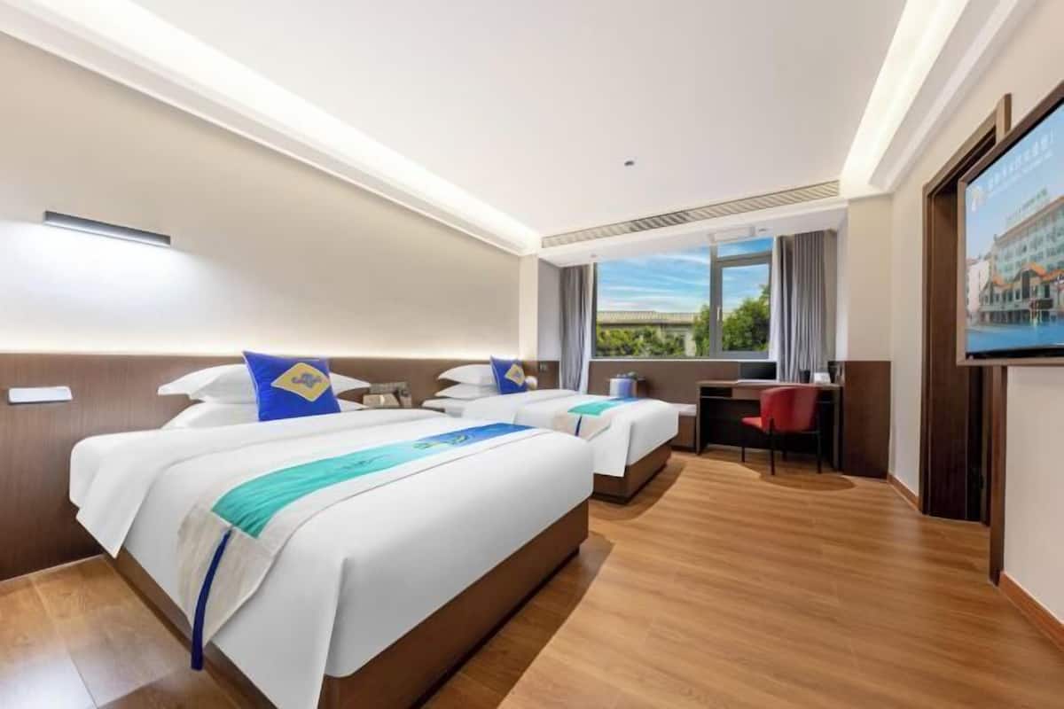 Habitación de hotel con dos camas, un escritorio y una televisión.