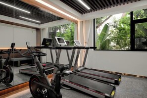 Un gimnasio con cintas de correr, una máquina elíptica y una bicicleta estática.