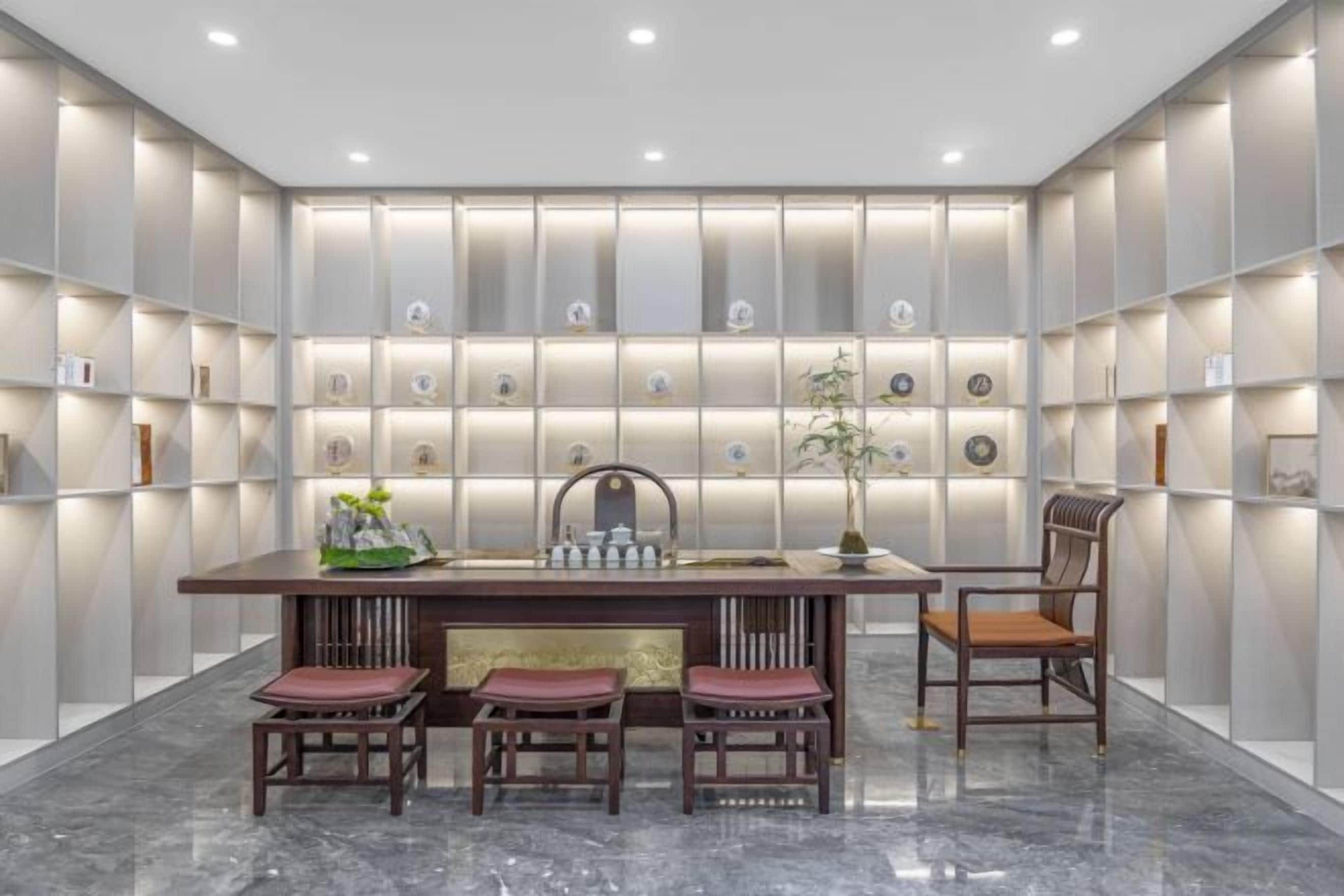 Un interior moderno con piso de mármol, una mesa de comedor central con sillas y estanterías iluminadas.