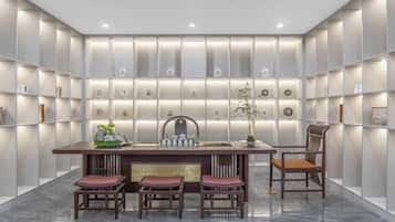 Un interior moderno con piso de mármol, una mesa de comedor central con sillas y estanterías iluminadas.