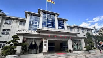 A hotel with a traditional architectural style, featuring a prominent entrance with glass doors and a red carpet.