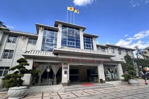 Un hotel de estilo arquitectónico tradicional, con una entrada destacada con puertas de cristal y alfombra roja.