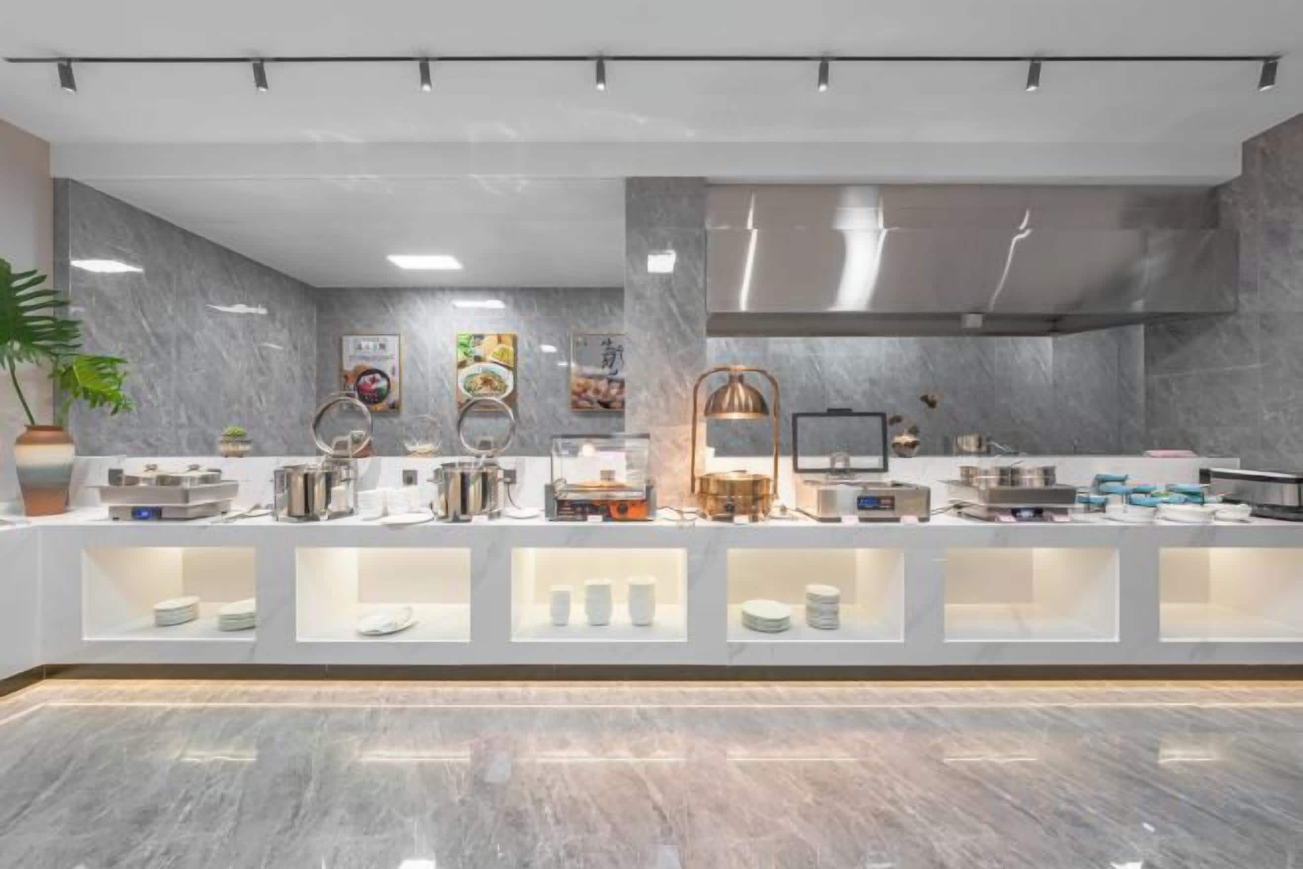 A modern kitchen with marble countertops, stainless steel appliances, and a variety of food items displayed.