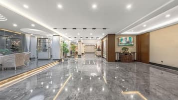 A hotel lobby with a marble floor, a reception desk, and a dining area.