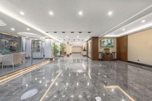 Un vestíbulo de hotel con piso de mármol, una recepción y un comedor.